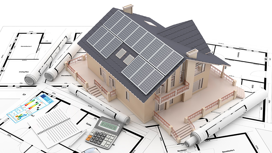 A 3D model of a house with solar panels on the roof is placed over architectural blueprints. Nearby are rolled-up plans, a calculator, and a pencil, suggesting a focus on sustainable home design and planning.